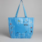 Blue bag with cartoon cat designs held by a hand on a white surface