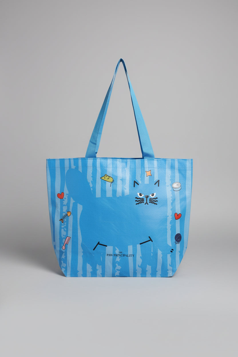 Blue bag with cartoon cat designs held by a hand on a white surface