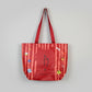 Red bag with cartoon dog designs held by a hand on a white background