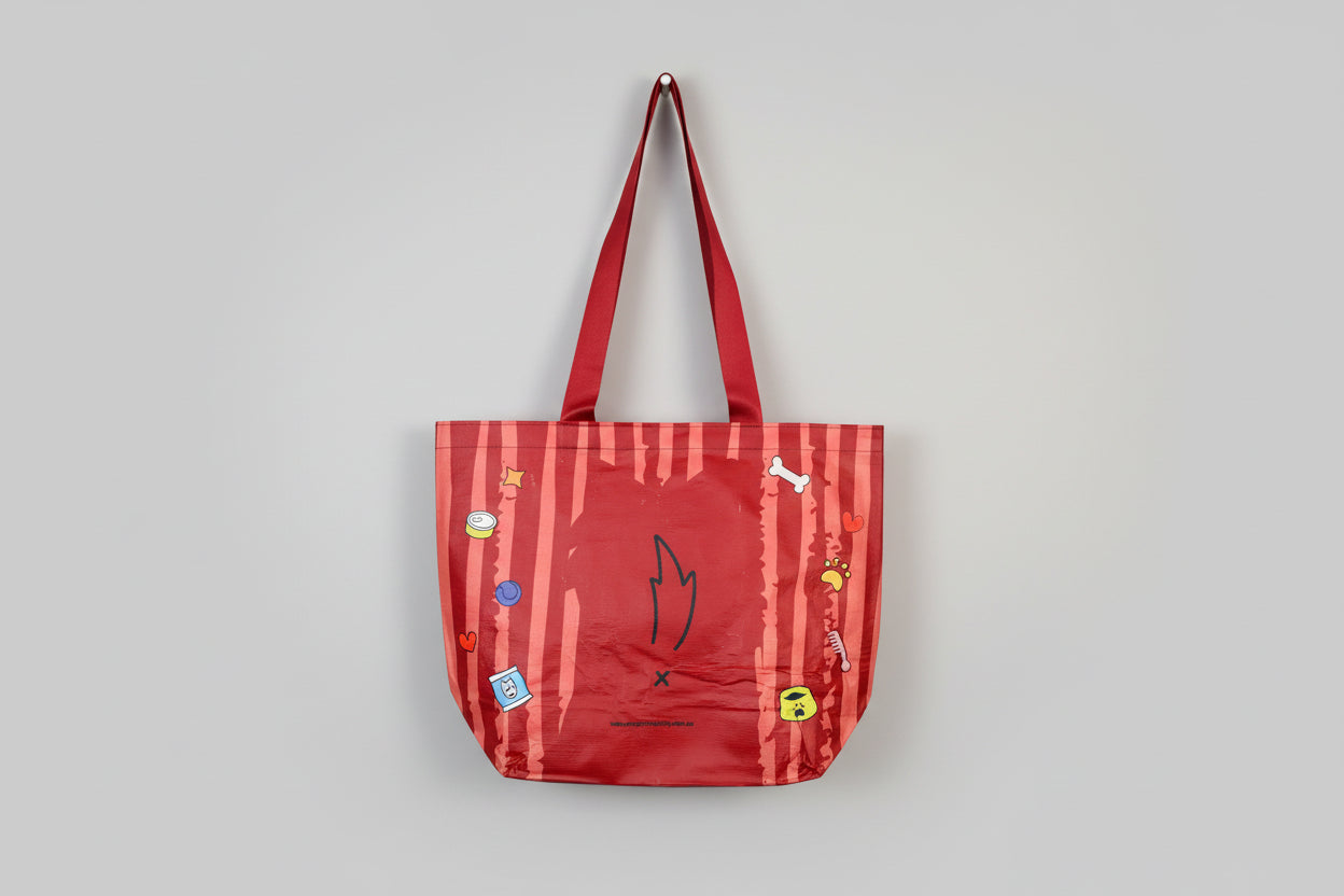 Red bag with cartoon dog designs held by a hand on a white background