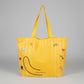 Yellow tote bag cat with cartoon designs held by a hand on a white surface