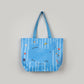 Blue bag with cartoon cat designs held by a hand on a white surface