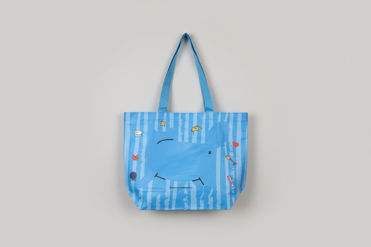 Blue bag with cartoon cat designs held by a hand on a white surface